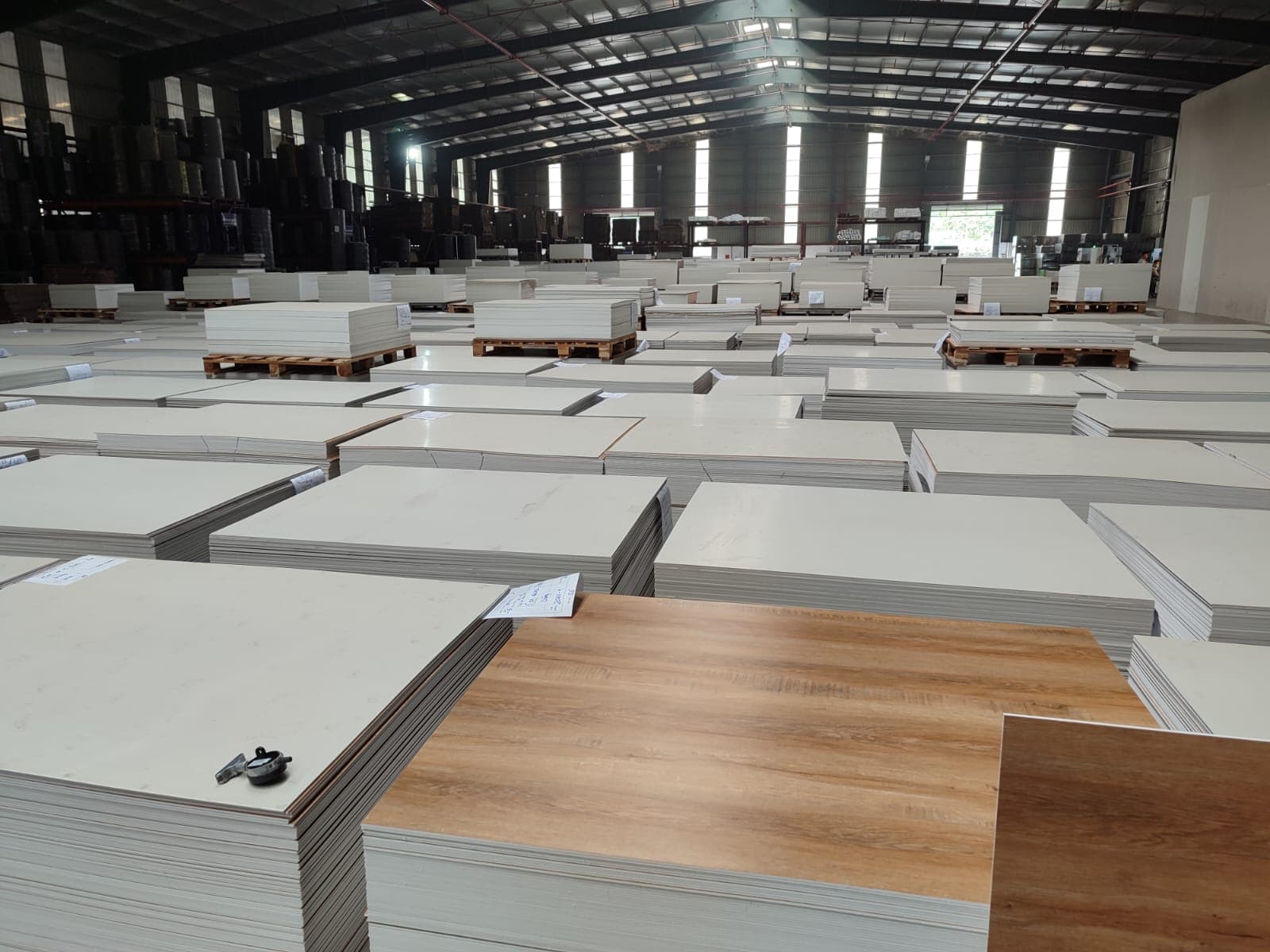 Stacks of flooring panels with a wood-grain sample on top